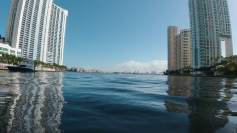 shot-from-a-small-watercraft-as-it-travels-a-narrow-waterway-in-Miami-Florida-with-tall-buildings-on-both-sides