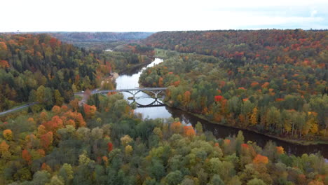 Aerial-View-of-the-Sigulda-Bridge-and-Cable-Car-Over-Gauja-River-During-Golden-Autumn-Season-in-Latvia