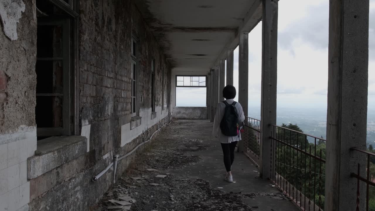 caramulo sanatorium 오래된 버려진 건물의 긴 발코니에서 걷는 여성의 뒷모습