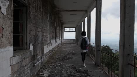 back view of woman walking on long balcony of caramulo sanatorium old abandoned building