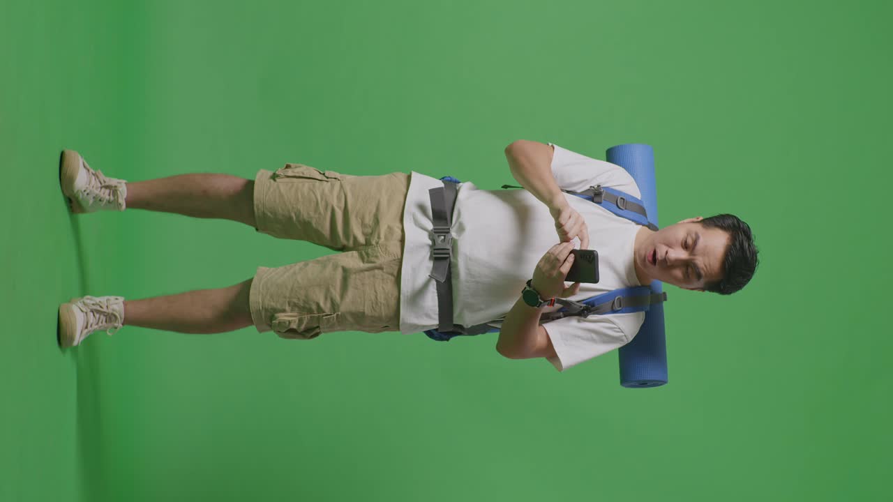 hombre usando un teléfono inteligente mientras lleva una mochila