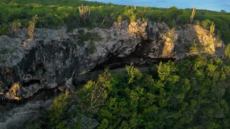 aerial orbit of sharp jagged rock cliff face as golden hour light spreads on rocks