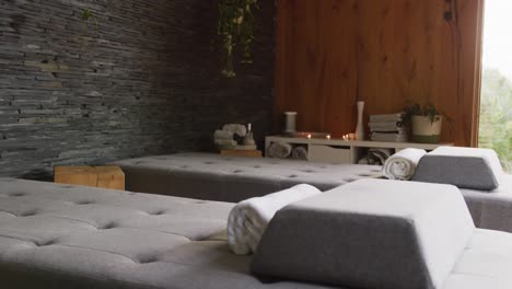 vertical video of massage treatment room at health spa, with massage tables towels and lit candles