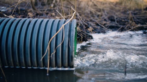 slomo shot of water running out of sewage pipe into nature, slow pan