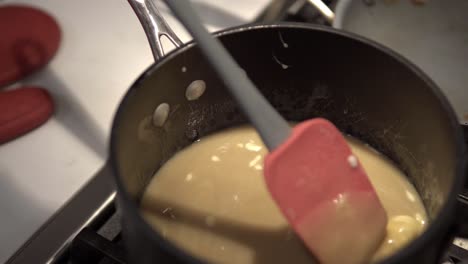 a young girl stirs a caramel mix heating up on the stove while baking millionaire shortbread cookies-1