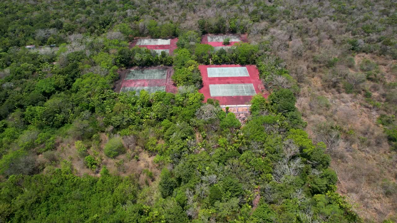 complejo abandonado cerrado con canchas de tenis cubiertas de vegetación - vista aérea de la selva