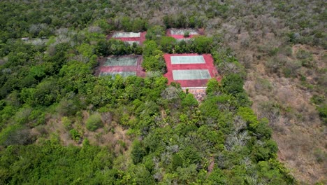 Closed-Abandoned-Resort-with-overgrown-tennis-courts--aerial-view-of-jungle