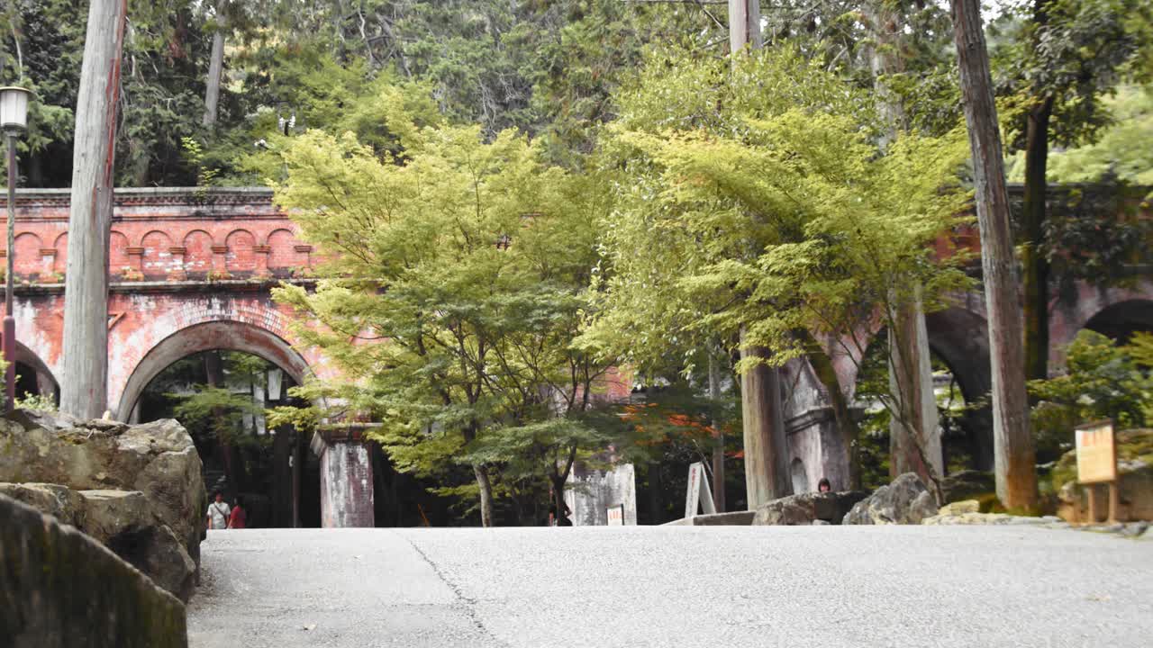tiro de diapositiva del puente de ladrillo detrás de los árboles en kyoto, japón 4k cámara lenta