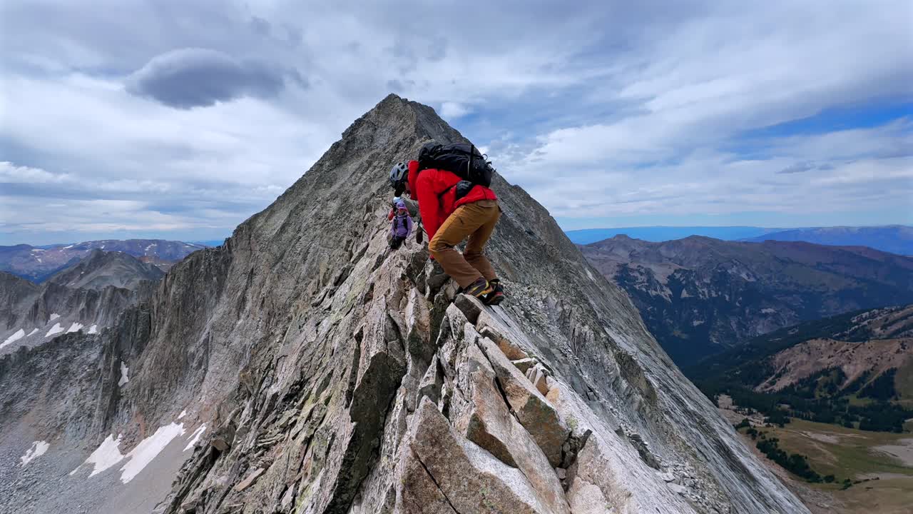 Hiking Capitol Peak Wilderness Knifes Edge North East Ridge Trail scrambling rock climbing Rocky Mountains Colorado 14er boulders summer blue sky morning sunny rugged terrain pan left