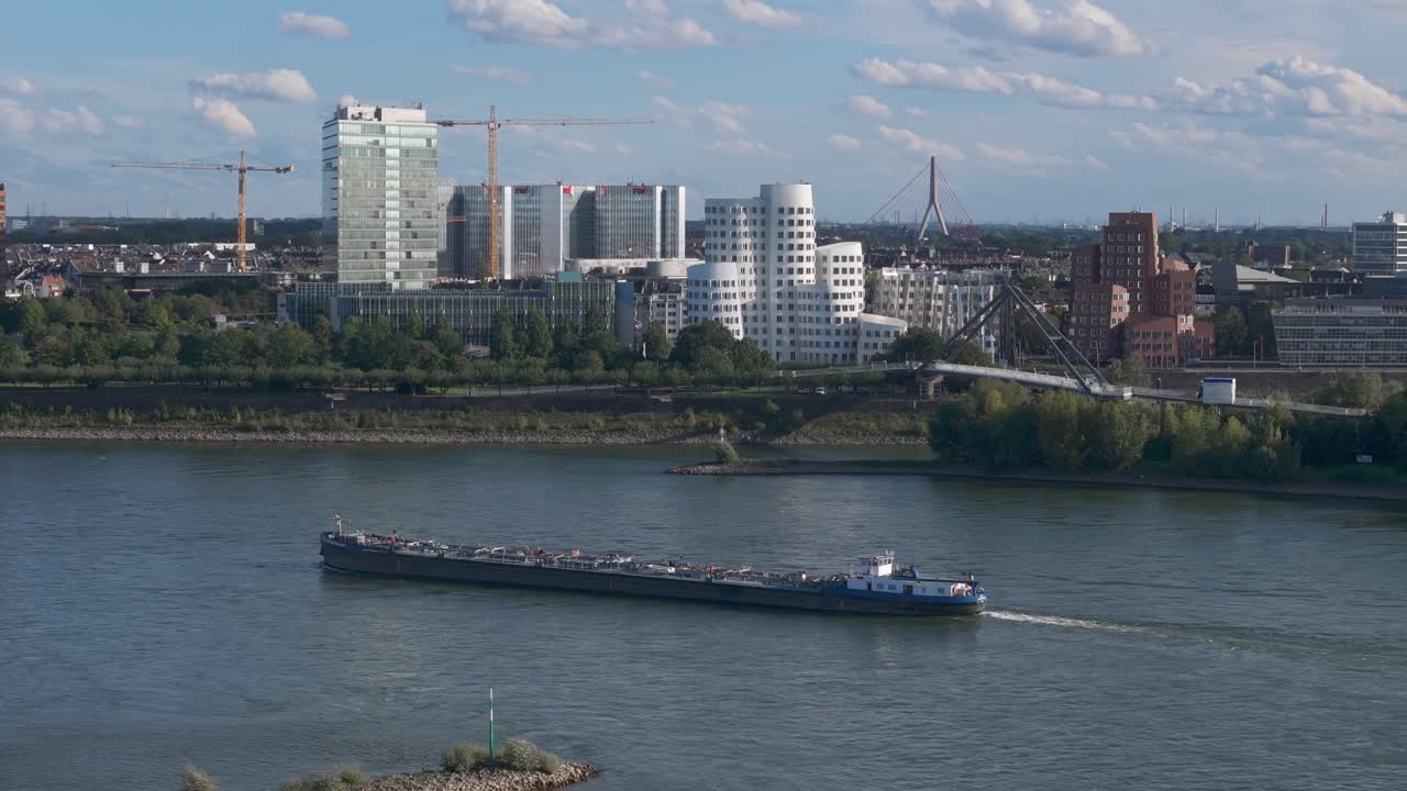 A massive cargo vessel glides along the Rhine River in D&uuml;sseldorf