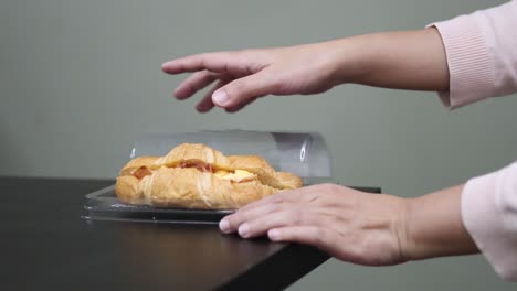 hands removing a croissant from packaging, sharing it