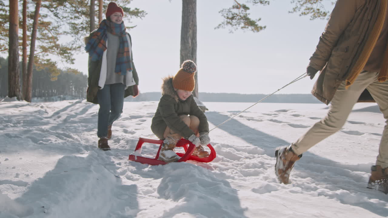 Far som trekker datter på slede i skogen