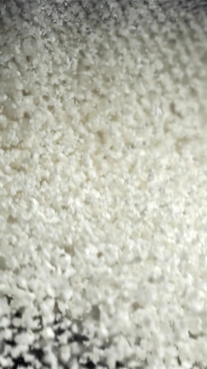 Macro di polvere granulare bianca che cade e si accumula