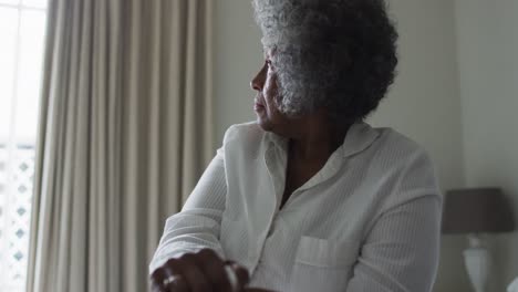 senior african american woman holding walking stick sitting on the bed at home