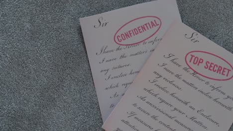 close up of aged documents labeled top secret and confidential placed on a soft fabric