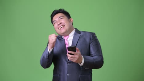 초록색 배경에 젊은 잘생긴 과체중 아시아 사업가