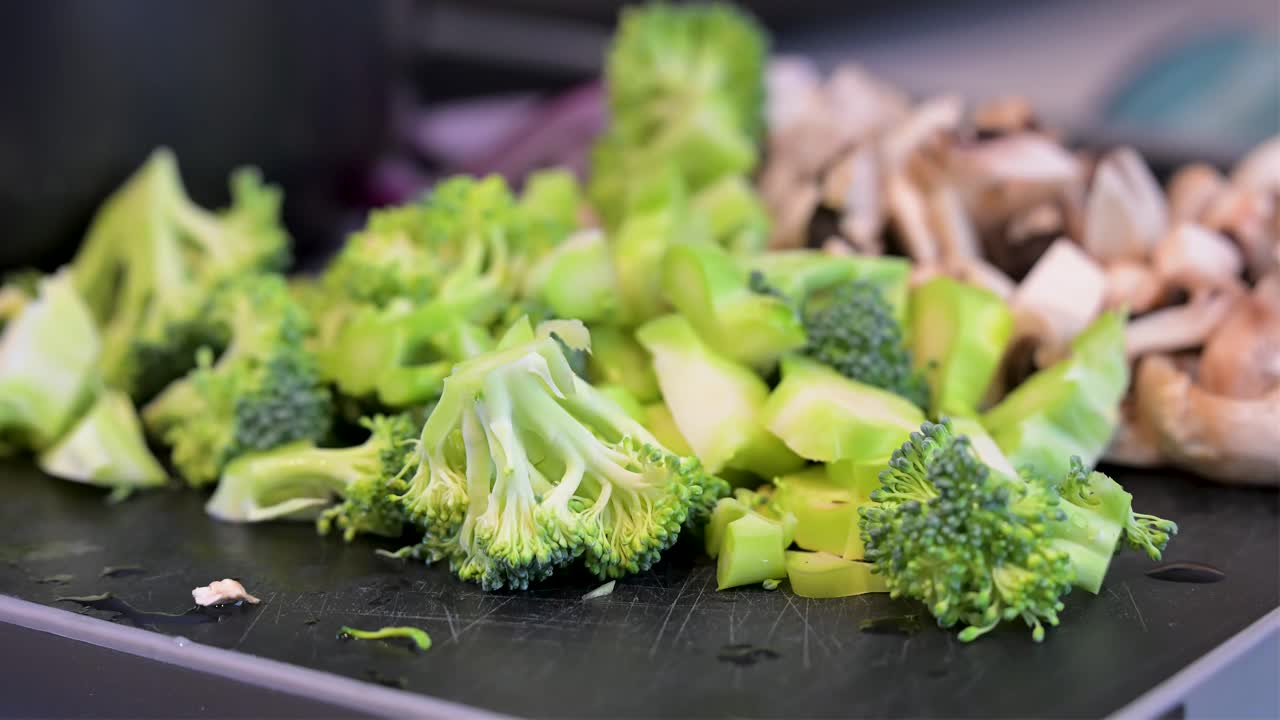 The crisp texture of broccoli florets is beautifully rendered in this shallow depth of field shot. Freshly chopped vegetables create a wholesome and inviting culinary scene
