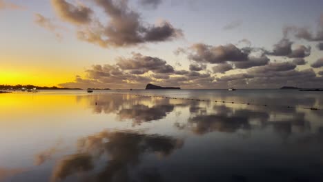 a beautiful upward reveal over the glossy sunset tainted sea water finishing on gunner's quoin island standing tall in the background.