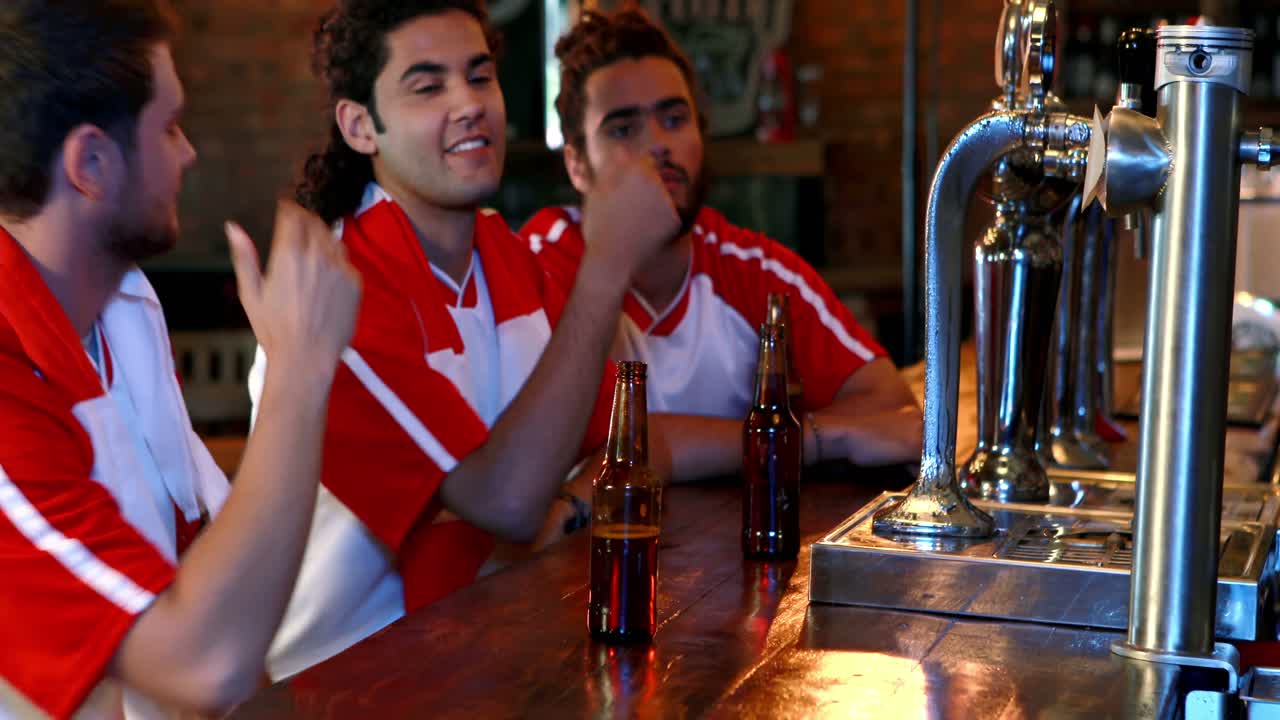 amigos molestos interactuando mientras beben cerveza en el mostrador del bar
