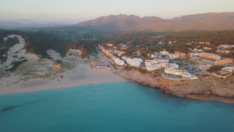 Impresionante-Vista-Aérea-De-La-Costa-En-El-Norte-De-Mallorca---Cala-Mesquida-Con-Hoteles-Mientras-Sale-El-Sol---Zona-Turística-De-Mallorca