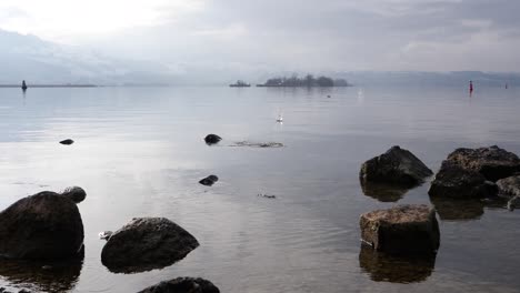persona saltando rocas en la superficie del agua en el lago en suiza, cámara lenta