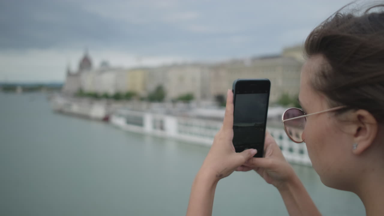 mujer tomando una foto del paisaje urbano desde el puente
