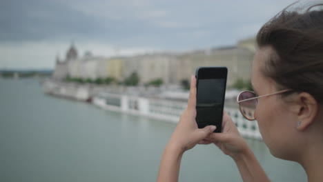 woman taking photo of cityscape from bridge