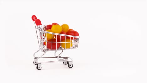el carrito del supermercado se mueve lleno de tomates de uva roja y amarilla. aislados en el fondo blanco. primer plano. macro.