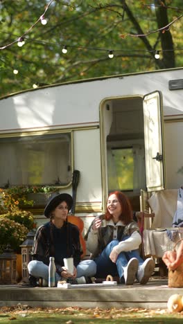 two women relaxing by a trailer in autumn