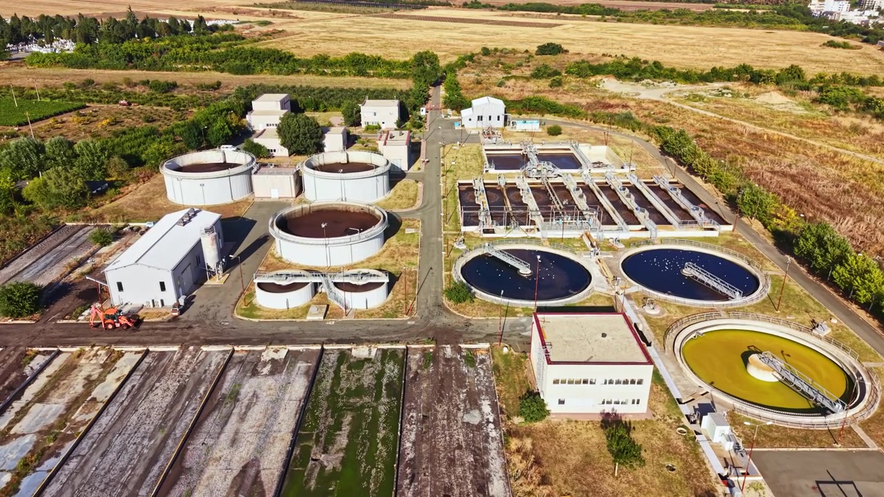 Water treatment facility with processing tanks and buildings in a rural area during daylight hours