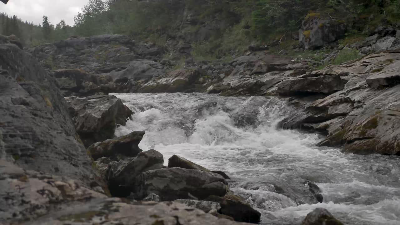 Fiume in lento movimento con rocce su entrambi i lati in Norvegia, piccola cascata