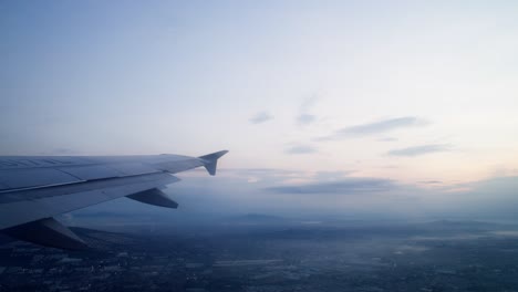 view of airplane wing as plane ascends and turns left, soaring through open sky