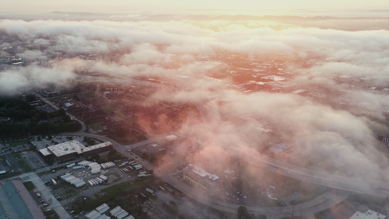 Sunlight breaks through fog, revealing warehouses and streets in Chattanooga’s industrial district.