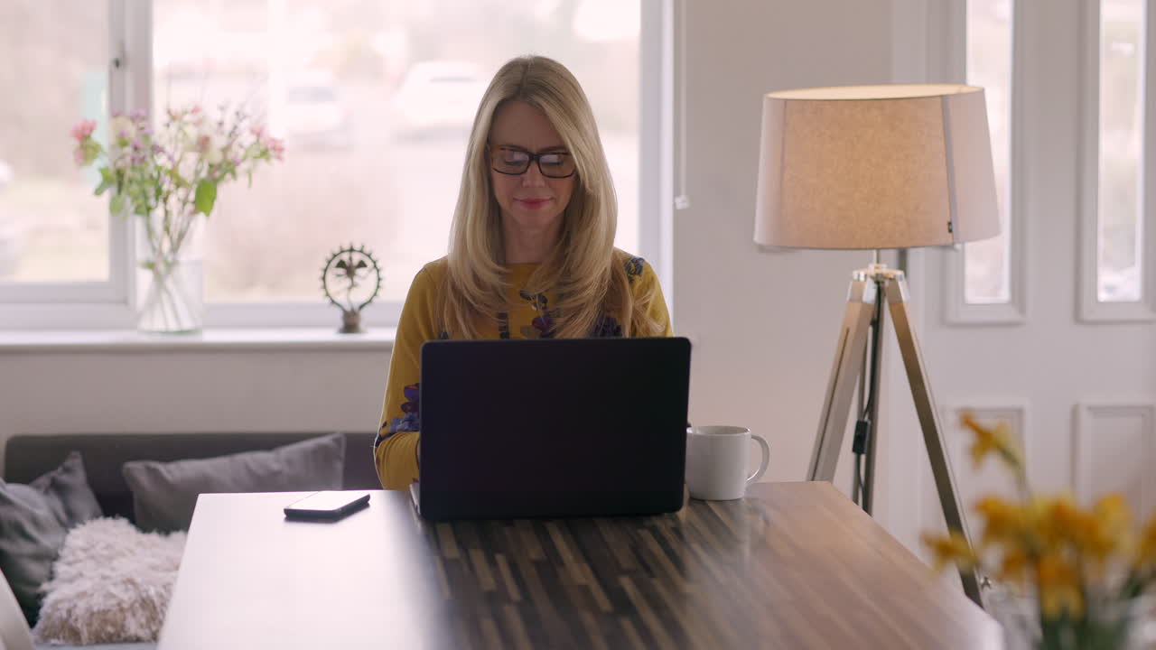 Frau nutzt Laptop und Telefon zu Hause