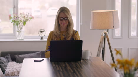 woman using laptop and phone at home
