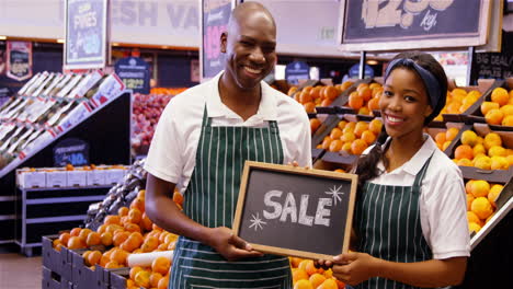 smiling staffs holding sale signboard in organic section