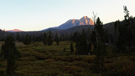 aerial drone landscape nature shot flying by trees and a river towards the beautiful red castle lake mountain up in the high uinta's between utah and wyoming on a backpacking trip during a sunset