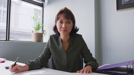 Portrait-of-biracial-businesswoman-having-video-call-and-looking-at-camera-at-office