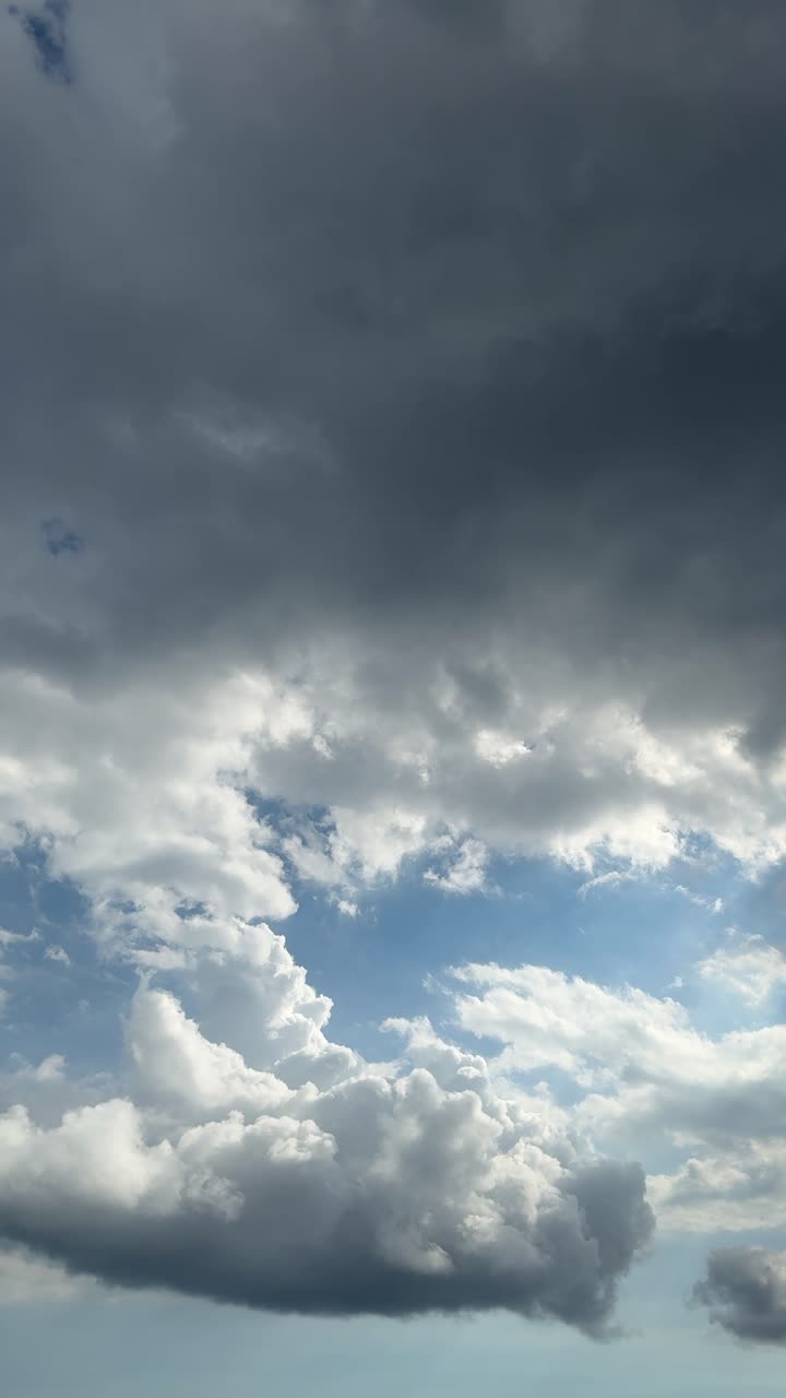 Pemandangan Awan Dinamis dengan Awan Gelap dan Putih Bergerak Melintasi Langit Biru