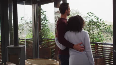 Smiling-mixed-race-couple-enjoying-the-view-while-standing-together-in-the-balcony-at-vacation-home