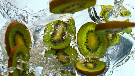 rebanadas de kiwi cayendo agua en súper cámara lenta de cerca. la fruta cayó en líquido