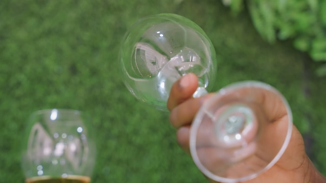 Moment intime autour du vin. Main agrippant un verre en soirée. Rencontre rapprochée avec un verre de vin lors d'une paisible soirée au jardin. Main tenant un verre de vin contre un mur de jardin lors d'une soirée romantique.