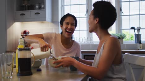 Mixed-race-lesbian-couple-preparing-and-eating-breakfast-in-kitchen