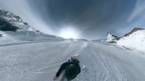 Ein-Mann,-Der-Schnell-Die-Piste-Hinunterfährt-Und-An-Anderen-Leuten-Vorbeikommt,-Während-Die-Kamera-Vor-Ihm-Mit-Blick-Auf-Das-Matterhorn-Schwenkt