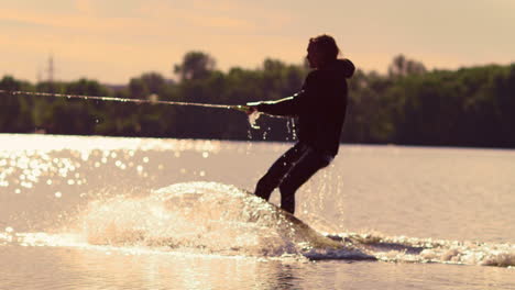 Der-Mann-Beginnt-Bei-Sonnenuntergang-Mit-Dem-Wakeboarden.-Extremer-Lebensstil.-Reiten-Auf-Dem-Wasser