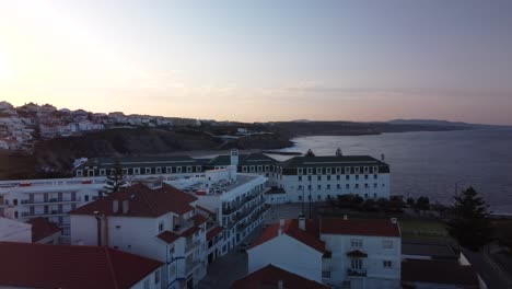 vista aérea del paisaje marino de la costa de ericeira durante el amanecer, edificio del hotel junto al océano, portugal