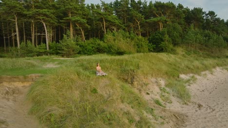 aerial establishing view of beautiful young romantic caucasian girl in a long dress on the white sand beach, sunny summer evening, sunset, golden hour, wide drone orbit shot