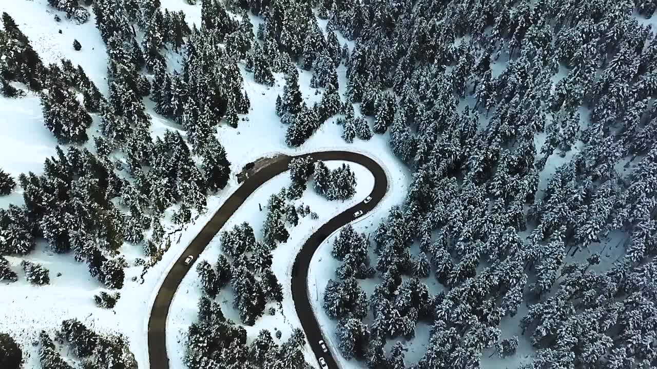 Aerial view over an icy road on a snowed mountain during a winter afternoon