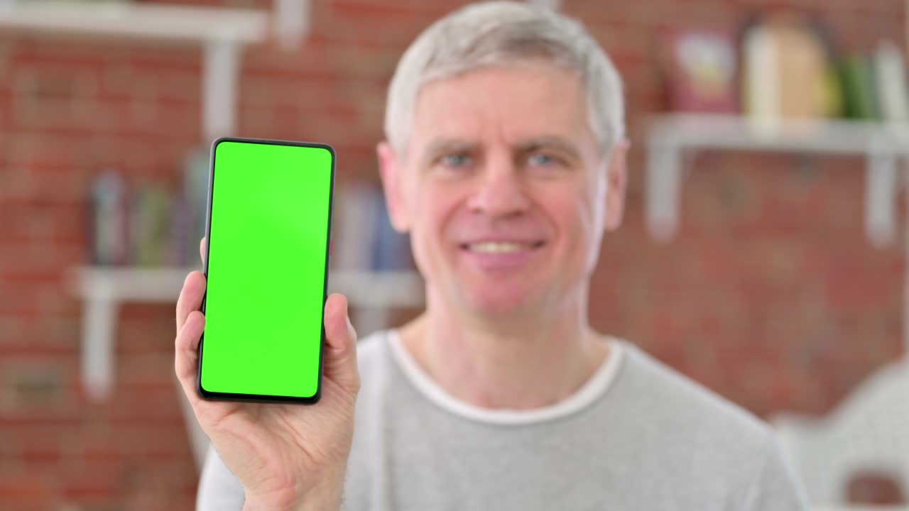 크로마 스크린 을 가진 스마트폰 을 들고 있는 노인