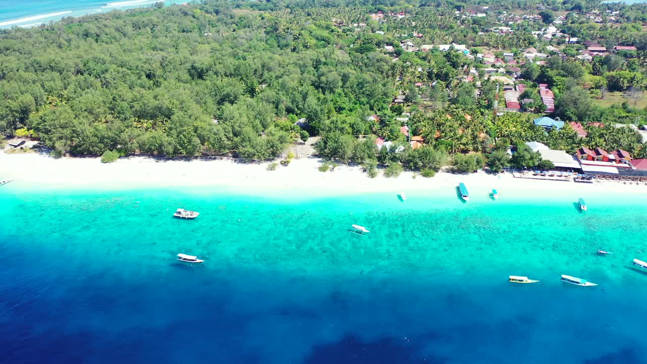 Boats floating over blue azure sea, washing white sandy beach of tropical island with lush vegetation around villas, holiday resorts in Bali